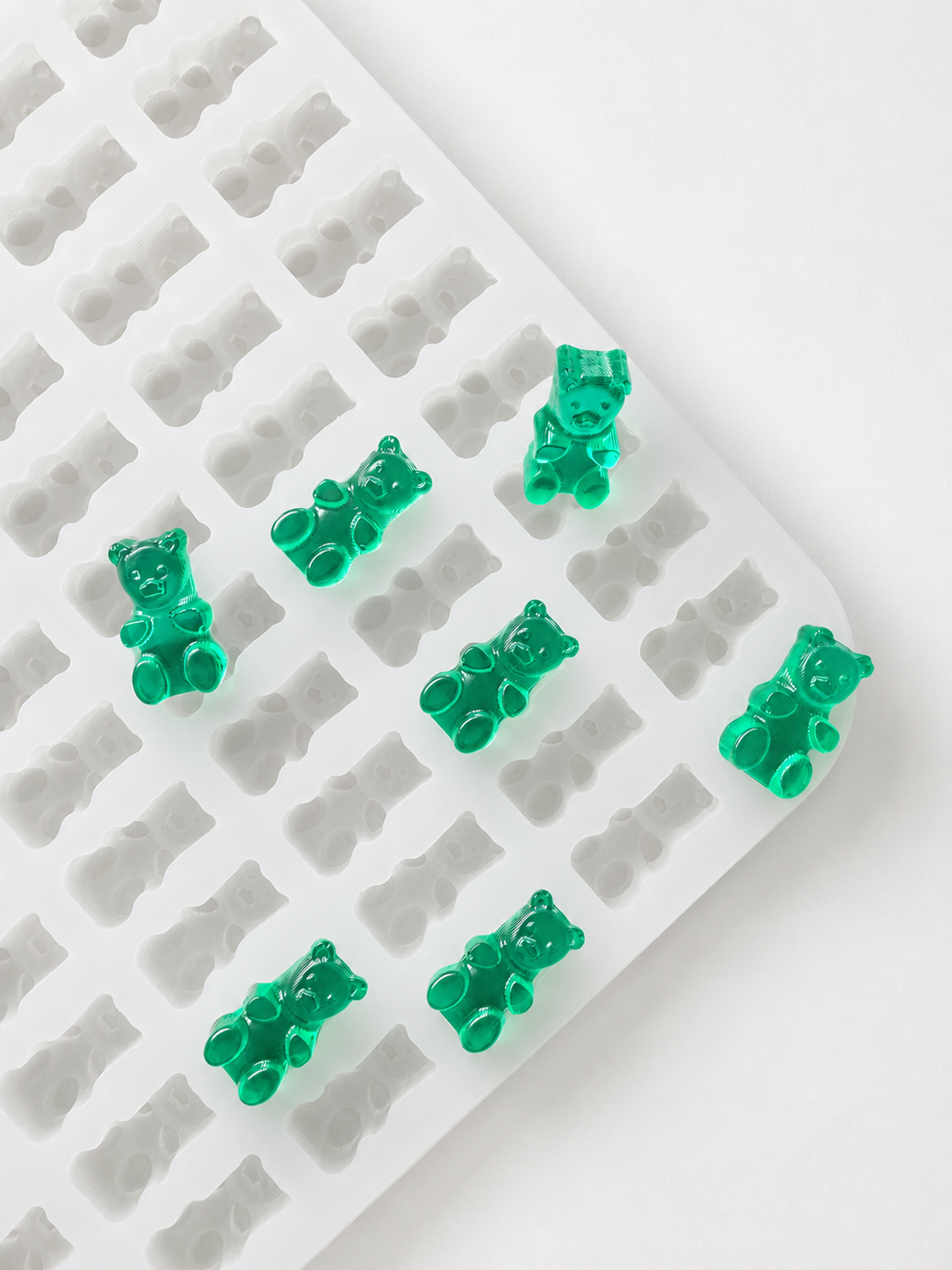 Commercial gummy bear mold with finished translucent emerald green gummy bears