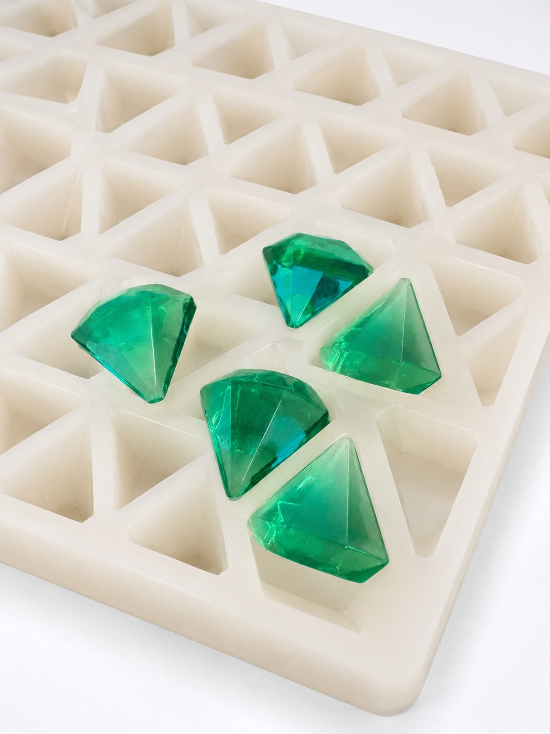 Emerald green diamond gummies beside a commercial silicone gummy mold for formulation comparison