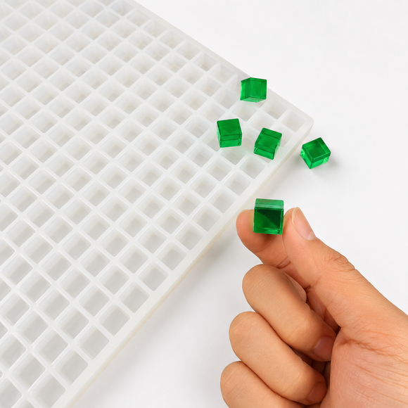 Close-up van een smaragdgroene 1 mL kubusgummy naast de vorm met 736 holtes