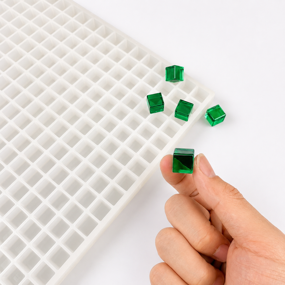 Hand met doorschijnende smaragdgroene 1 mL kubusgummy naast de vorm