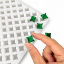Hand pressing an emerald green gummy in a 2mL star gummy mold with 192 cavities on a white background