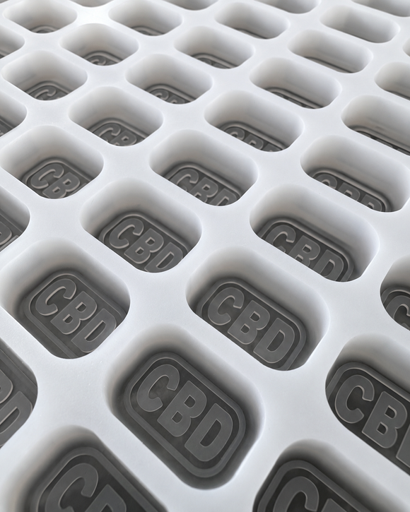 Close-up of 4mL brick gummy mold cavities with embossed regulatory symbol